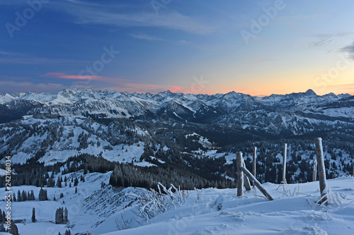 Beautiful colorful illuminated sky after sunset over the Allgeau Alps (Bavaria, Germany) at a cold winter day. Snow-covered alpine landscape with forests and rocky mountains. © Andreas Föll