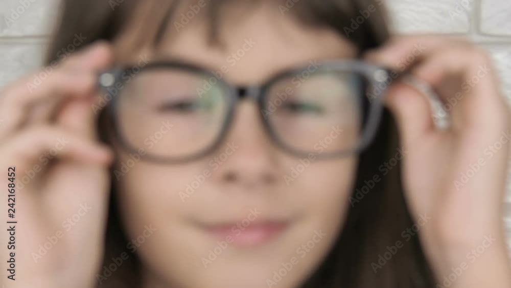 A child with poor eyes wears glasses. Beautiful little girl puts on glasses. A child with poor eyes wears glasses. Beautiful little girl puts on glasses.