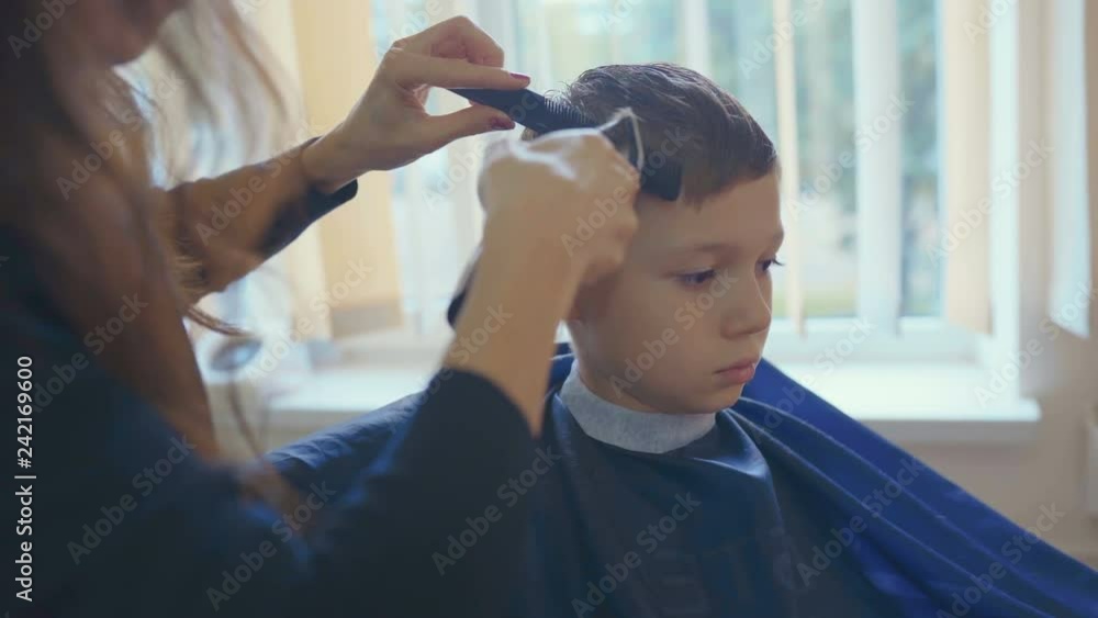 Hairdresser cutting hair with barber scissors in children hairdressing salon. Hairdresser cutting hair with barber scissors in children hairdressing salon.