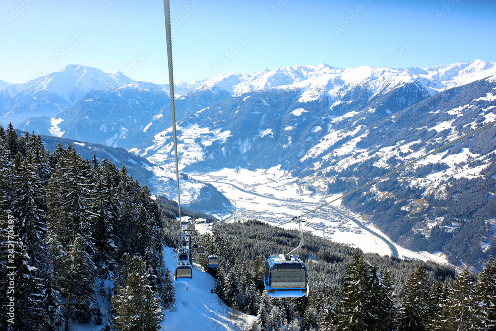 People enjoying skiing on prepared slopes in the Alps on sunny day. Modern comfortable gondola lift in Alpine ski resort. Perfect winter holidays destination for family. 