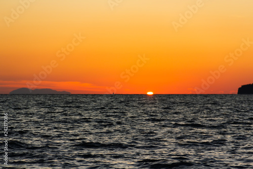 The sun is hiding the beach edge with orange sky