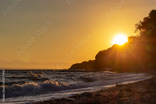 The rising sun peeks over the edge of the rocks near Tsilivi, Zakynthos, Greece photo