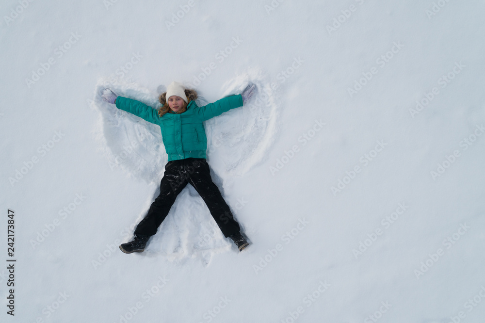 Girl on the snow shows an angel View from above