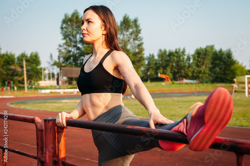 athletic young woman doing warm-up on sports field.
