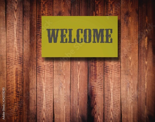 A sign of welcome, background wood, blurred image.