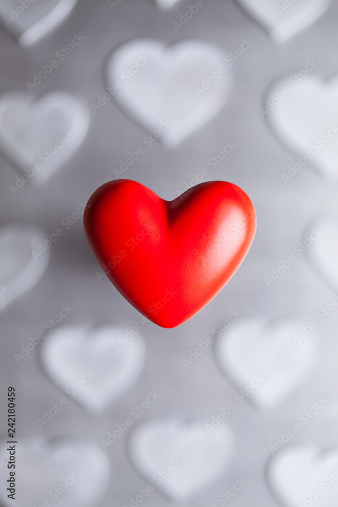 One red heart on the background of gray hearts as a symbol of Valentine's Day