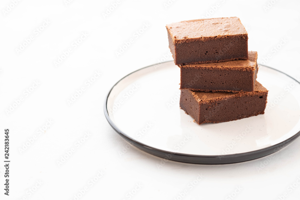 Chocolate brownie square pieces in stack on white plate. American traditional delicious dessert. Copy space. Chocolate brownie square pieces in stack on white plate. American traditional delicious dessert. Copy space.