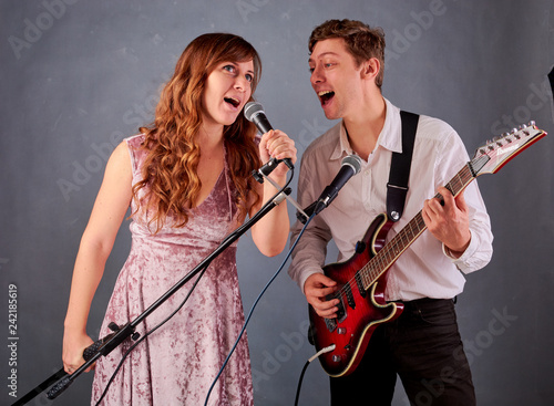 a guy and a girl stand and sing against