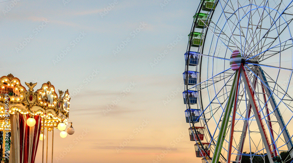 Ferris wheel in a fairground park next to a carousel