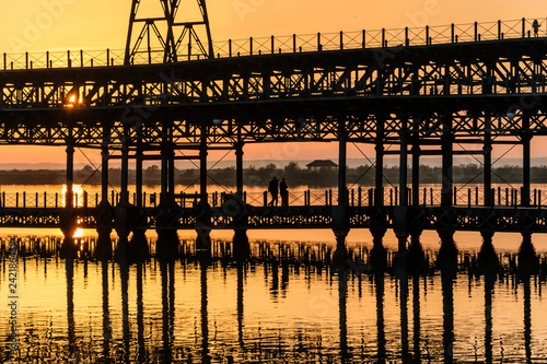 Three people walk on the dock of Rio Tinto at sunset, Huelva, Andalusia, Spain photo