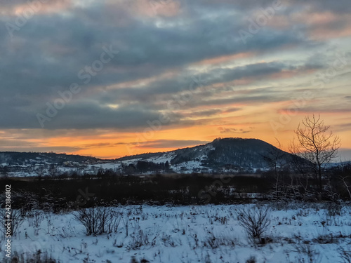 Winter landscape with field and trees during the sunset