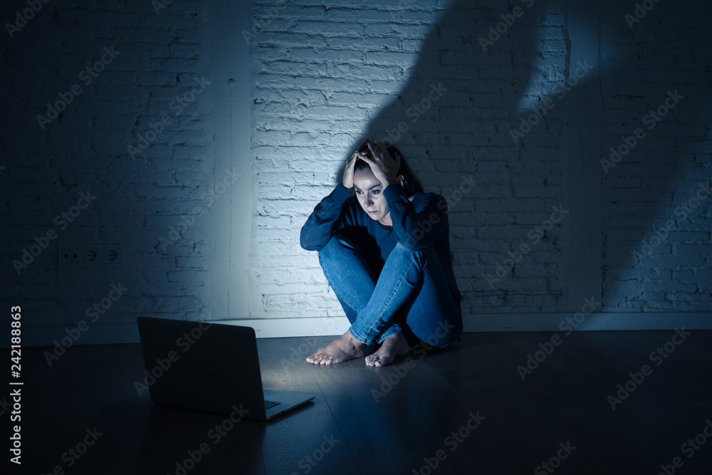 Woman suffering Internet cyber bullying and harassment feeling lonely looking afraid at laptop Woman suffering Internet cyber bullying and harassment feeling lonely looking afraid at laptop