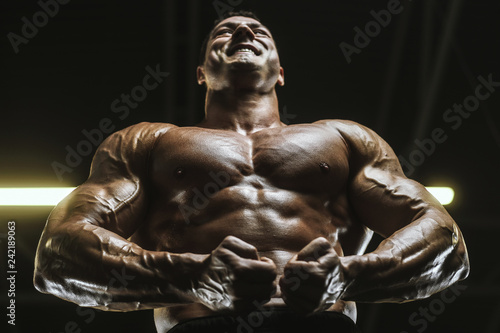 Handsome strong athletic men pumping up muscles workout bodybuilding concept background © antondotsenko