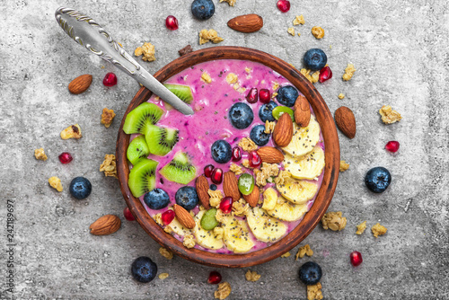Acai smoothie bowl topped with blueberry, fruits, chia and pumpkin seed, almonds and granola with spoon