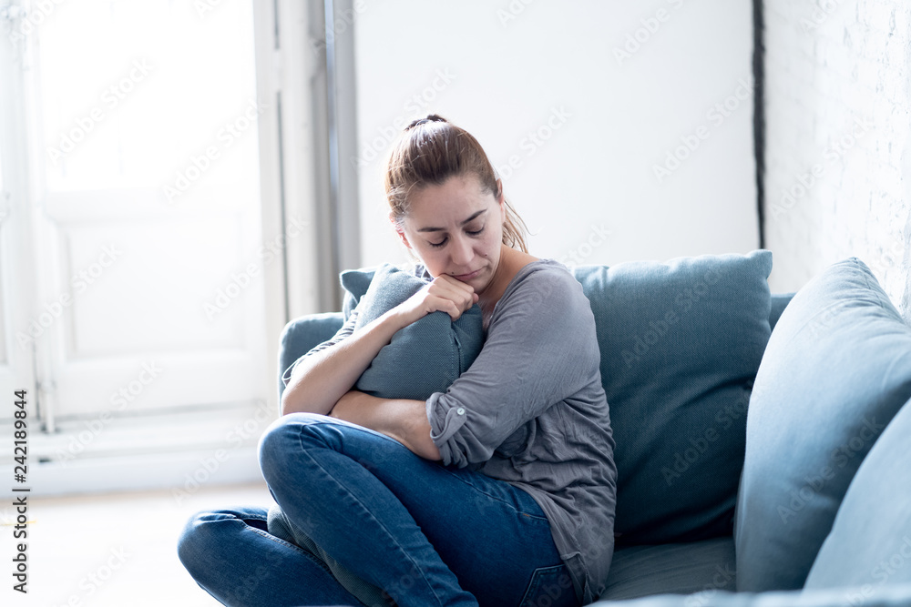 Young woman suffering from depression feeling sad and lonely on sofa at home Young woman suffering from depression feeling sad and lonely on sofa at home