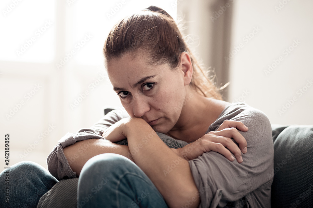 Young woman suffering from depression feeling sad and lonely on sofa at home Young woman suffering from depression feeling sad and lonely on sofa at home
