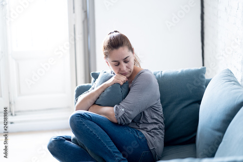 Young woman suffering from depression feeling sad and lonely on sofa at home