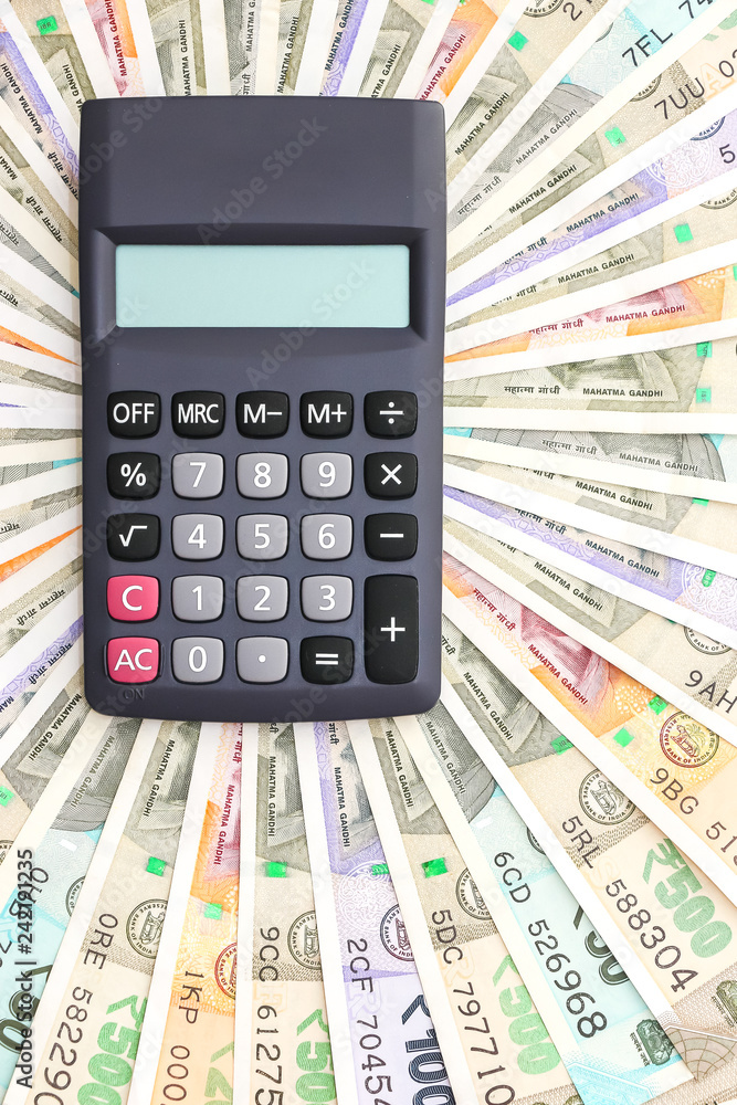 Close up view of calculator over brand new indian 10, 50, 100, 200, 500 and 2000 rupees banknotes. Colorful money pattern. Close up view of calculator over brand new indian 10, 50, 100, 200, 500 and 2000 rupees banknotes. Colorful money pattern.