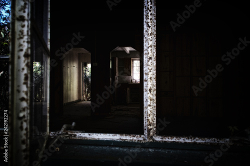 Looking into a dark abandoned home from window showing doorway and kitchen. Noise at 100%