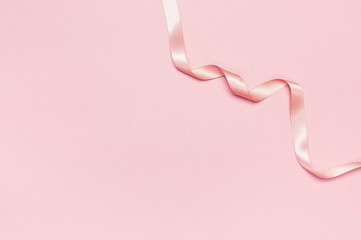 Pink satin ribbon on a pastel pink background top view Flat Lay with copy space. Element of holiday decoration, greeting card, birthday present, Valentine's Day, March 8.