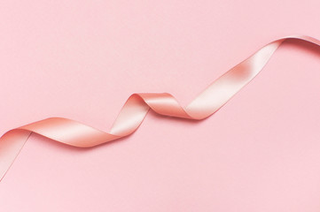 Pink satin ribbon on a pastel pink background top view Flat Lay with copy space. Element of holiday decoration, greeting card, birthday present, Valentine's Day, March 8.