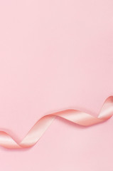 Pink satin ribbon on a pastel pink background top view Flat Lay with copy space. Element of holiday decoration, greeting card, birthday present, Valentine's Day, March 8.