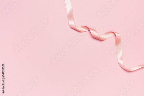 Pink satin ribbon on a pastel pink background top view Flat Lay with copy space. Element of holiday decoration, greeting card, birthday present, Valentine's Day, March 8.