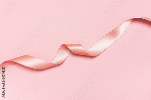 Pink satin ribbon on a pastel pink background top view Flat Lay with copy space. Element of holiday decoration, greeting card, birthday present, Valentine's Day, March 8.