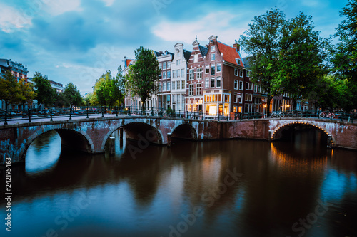 Famous Keizersgracht Emperor's canal in Amsterdam, dutch scenery with illuminated bridge at twilight, Netherlands