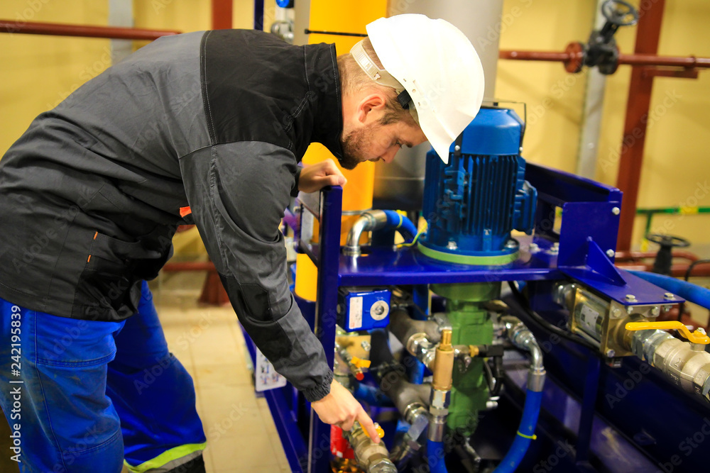 Engineer checking oil pump and pressure gauge in industrial plant.