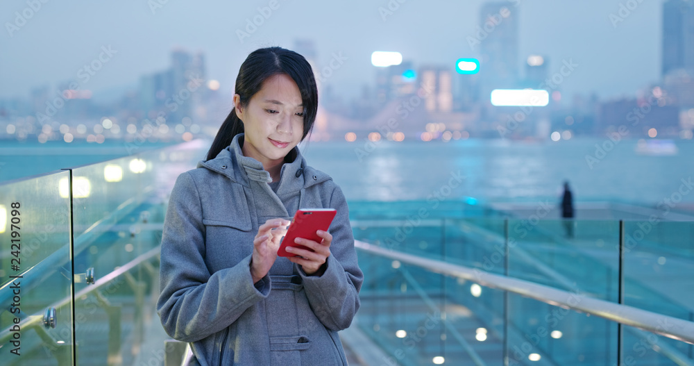 Woman check on mobile phone in city at night