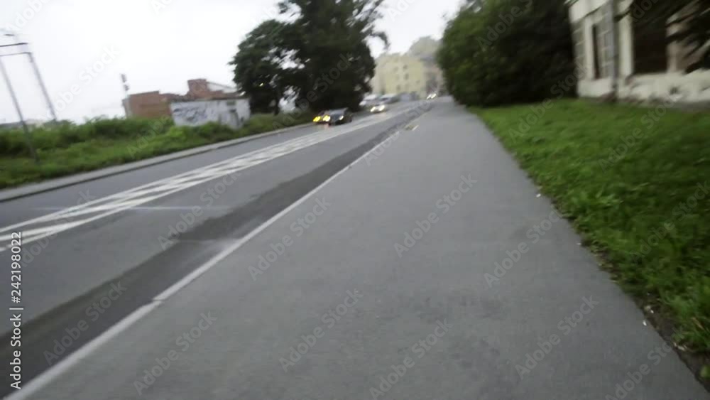 Person wearing white sneakers is running on sidewalk along big road with several cars and old building, and taking video on camera with shaking hand on cloudy day. Person wearing white sneakers is running on sidewalk along big road with several cars and old building, and taking video on camera with shaking hand on cloudy day.