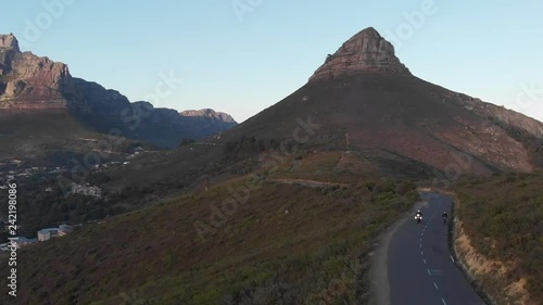aerial view of a single tour motorcyclist during sunrise on signal hill, Cape Town, with table mountain and lions head