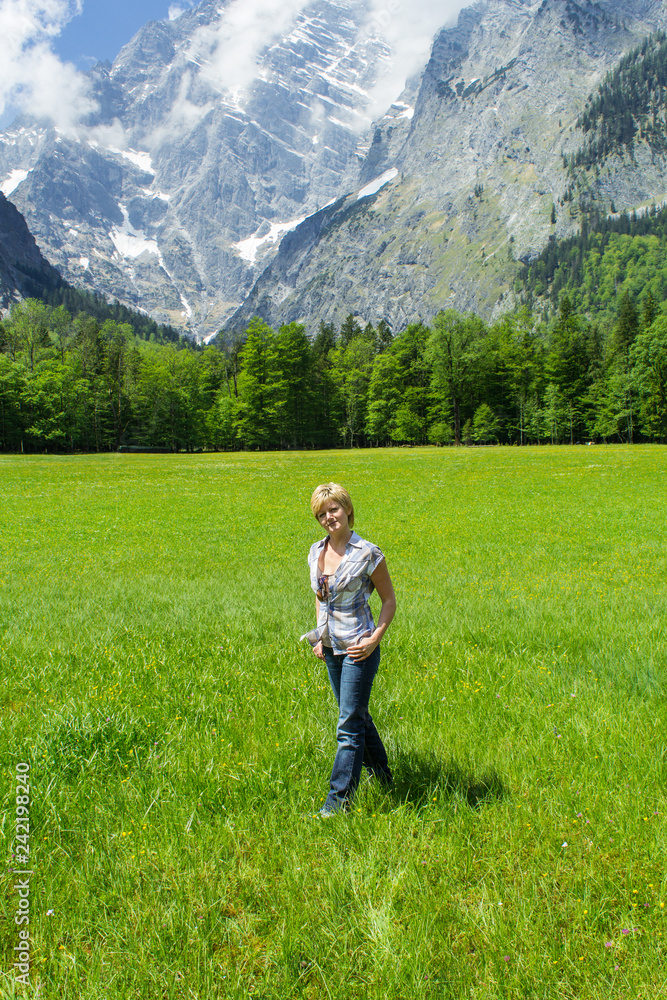 a young woman on the meadow with mountains in the background shows joy