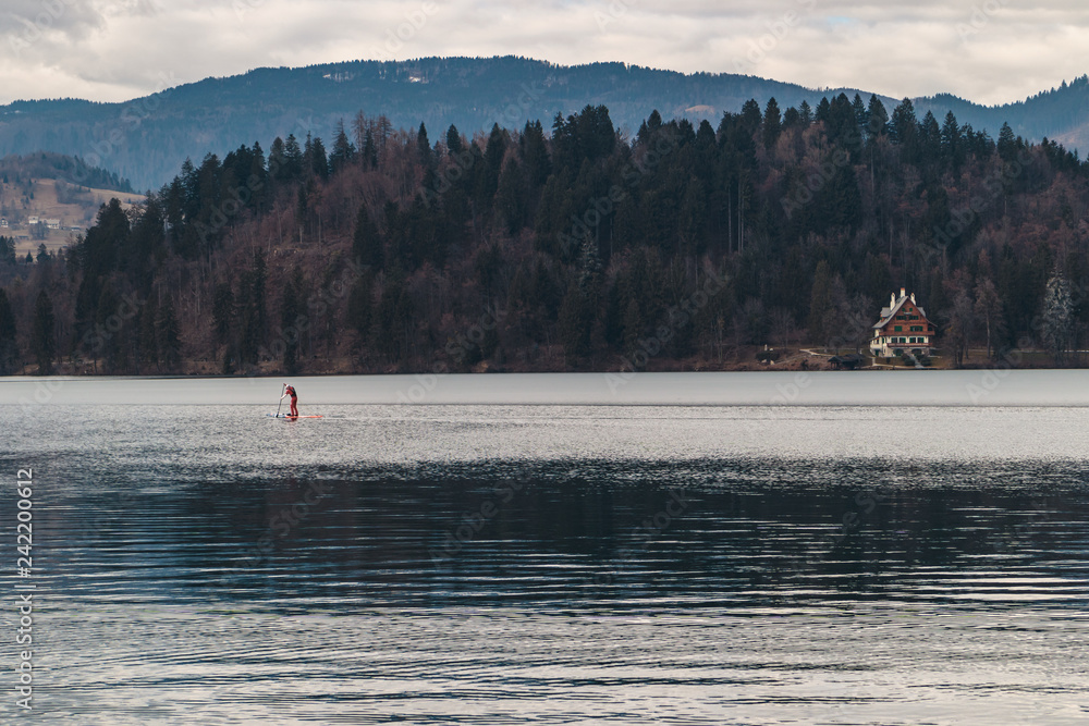 Standup paddle boarding on lake Bled and a house near the lake