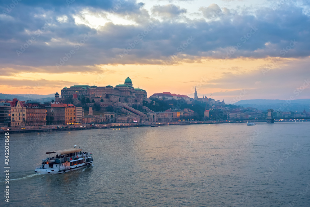 Danube river and a boat against Royal Palace of Buda in Budapest at sunset