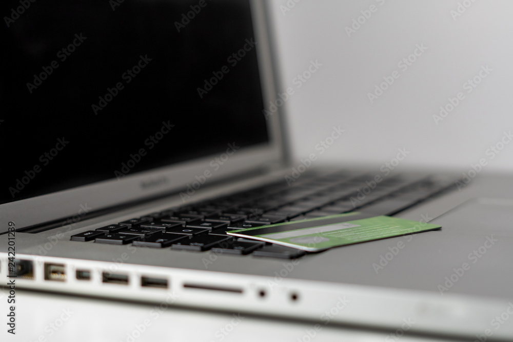 Online banking. Money management on the internet. Financial accounts. Credit or debit bank card on the silver laptop with black keys. Online banking. Money management on the internet. Financial accounts. Credit or debit bank card on the silver laptop with black keys.