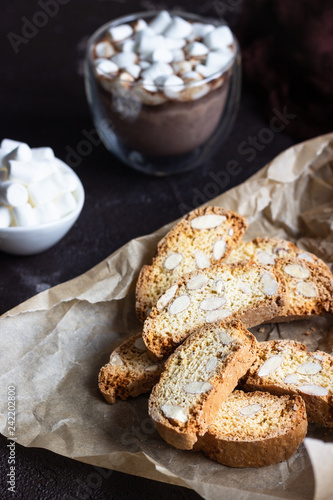 Biscotti or Cantuccini with almond and a glass cup of hot chocolate with marshmallows. Traditional Italian double baked cookies.
