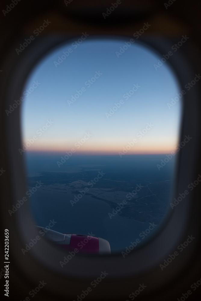 View from the window to airplane engine. Above the sky, on sunrise.