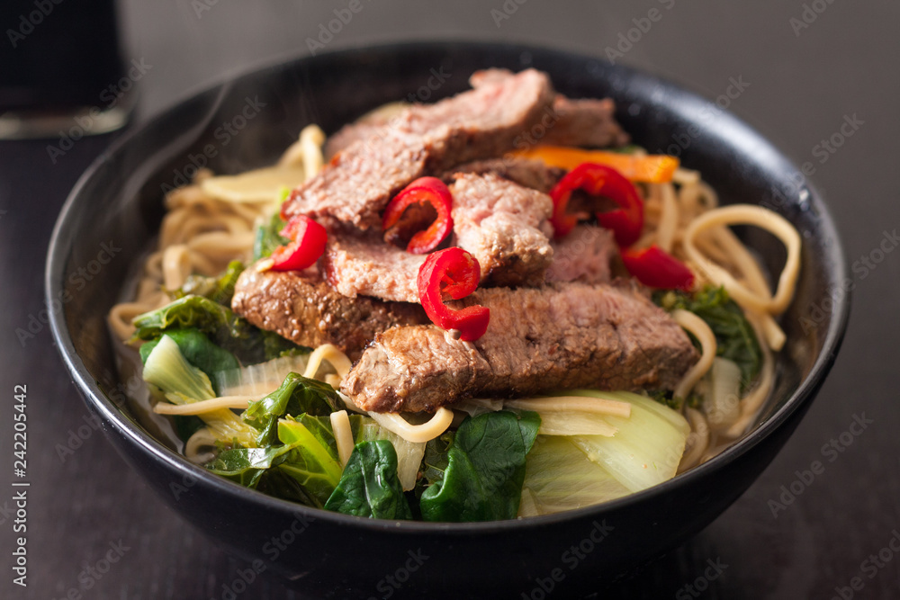 Close-up of a bowl of homemade ramen topped with slices of steak and fresh red chilli Close-up of a bowl of homemade ramen topped with slices of steak and fresh red chilli