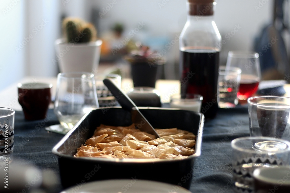 Pan of baklava on a table with coffee and wine. Baklava is traditonal Turkish pastry desset. Selective focus, moody lighting. Pan of baklava on a table with coffee and wine. Baklava is traditonal Turkish pastry desset. Selective focus, moody lighting.