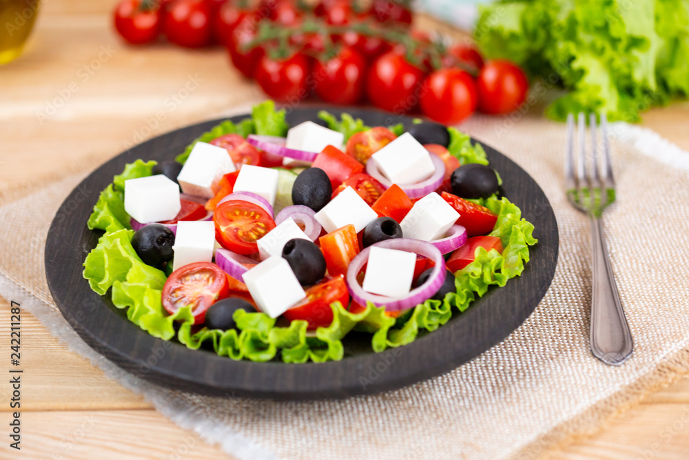 Greek salad with fresh vegetables on wooden background, feta cheese and black olives. Love for healthy raw food concept.