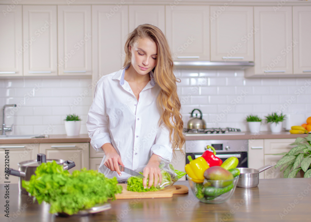 Beautiful girl in a white shirt prepares healthy food from vegetables Beautiful girl in a white shirt prepares healthy food from vegetables
