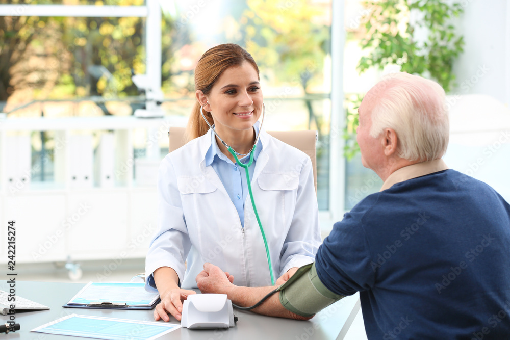 Obraz premium Doctor measuring blood pressure of elderly patient in hospital