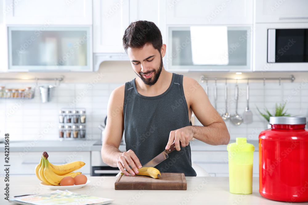 Young man preparing protein shake at table in kitchen Young man preparing protein shake at table in kitchen