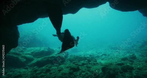Adventurous freediver woman exits epic underwater cave and surfaces