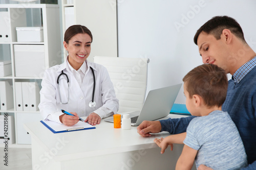 Father and son visiting pediatrician. Doctor working with patient in hospital