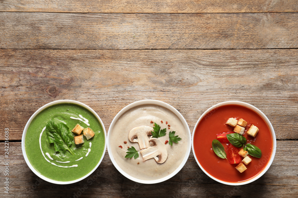 Various cream soups in bowls and space for text on wooden background, top view Various cream soups in bowls and space for text on wooden background, top view