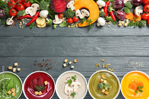 Various cream soups, ingredients and space for text on wooden background, flat lay. Healthy food