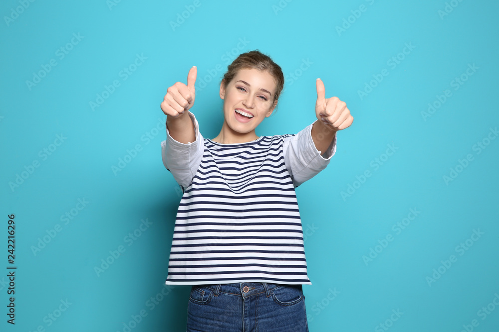 Happy young woman showing thumbs up on color background. Celebrating victory Happy young woman showing thumbs up on color background. Celebrating victory